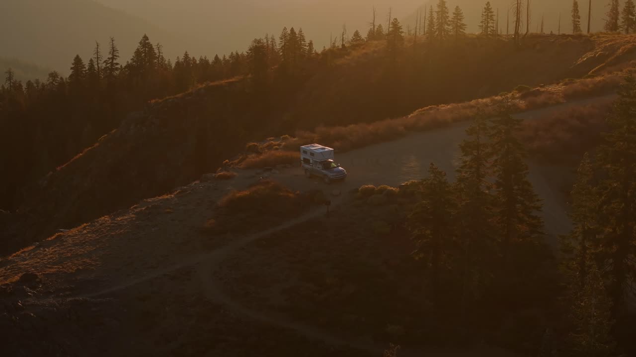 pop up camarote estacionado en un sendero de montaña pintoresco al atardecer rodeado de colinas boscosas