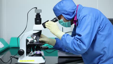 indian scientists checks microorganisms of corona virus with microscope. experiment using microscope for testing in laboratory.