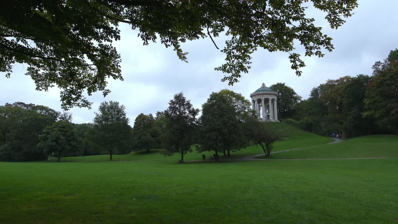 lapso de tiempo de gente caminando en el jardín inglés de munich con la vista en el popular templo monopteros en el centro del parque verde más grande de la capital bávara