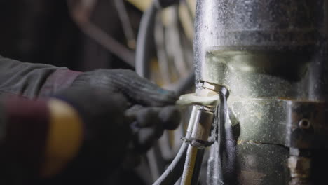 specialist in protective gloves tightens nut with wrench