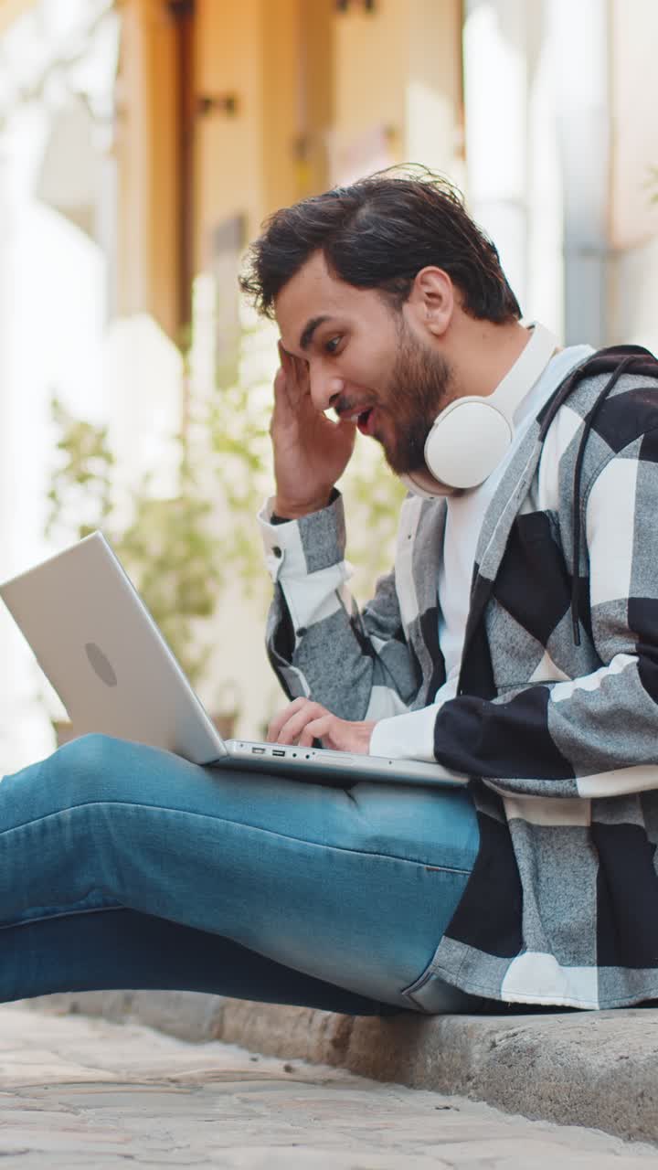 hombre feliz usando portátil celebrando ganar buen mensaje noticias lotería premio mayor victoria sentado en la calle