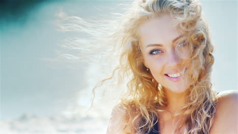 Junge-Frau-Lächelt-In-Die-Kamera-Und-Spielt-Mit-Ihrem-Schönen-Haar-Am-Strandporträt-Beach