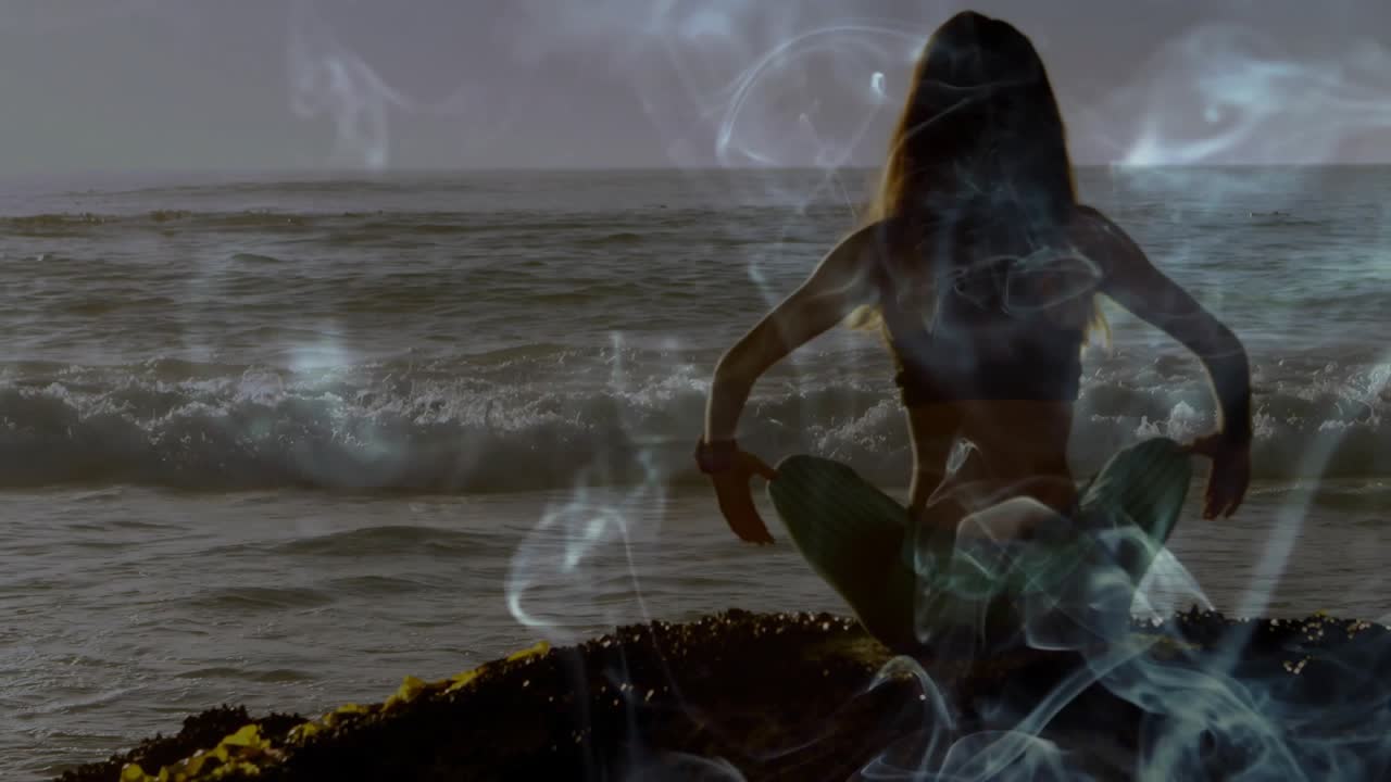 Dopo una pausa, insegnante di yoga su uno sperone roccioso che osserva le onde dell'oceano e la nebbia, alzando le braccia per celebrare l'orizzonte