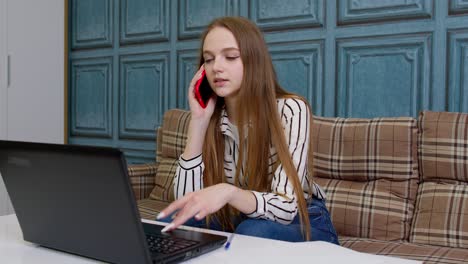 Young-business-woman-professional-consultant-talking,-on-mobile-phone,-using-laptop-at-home-office