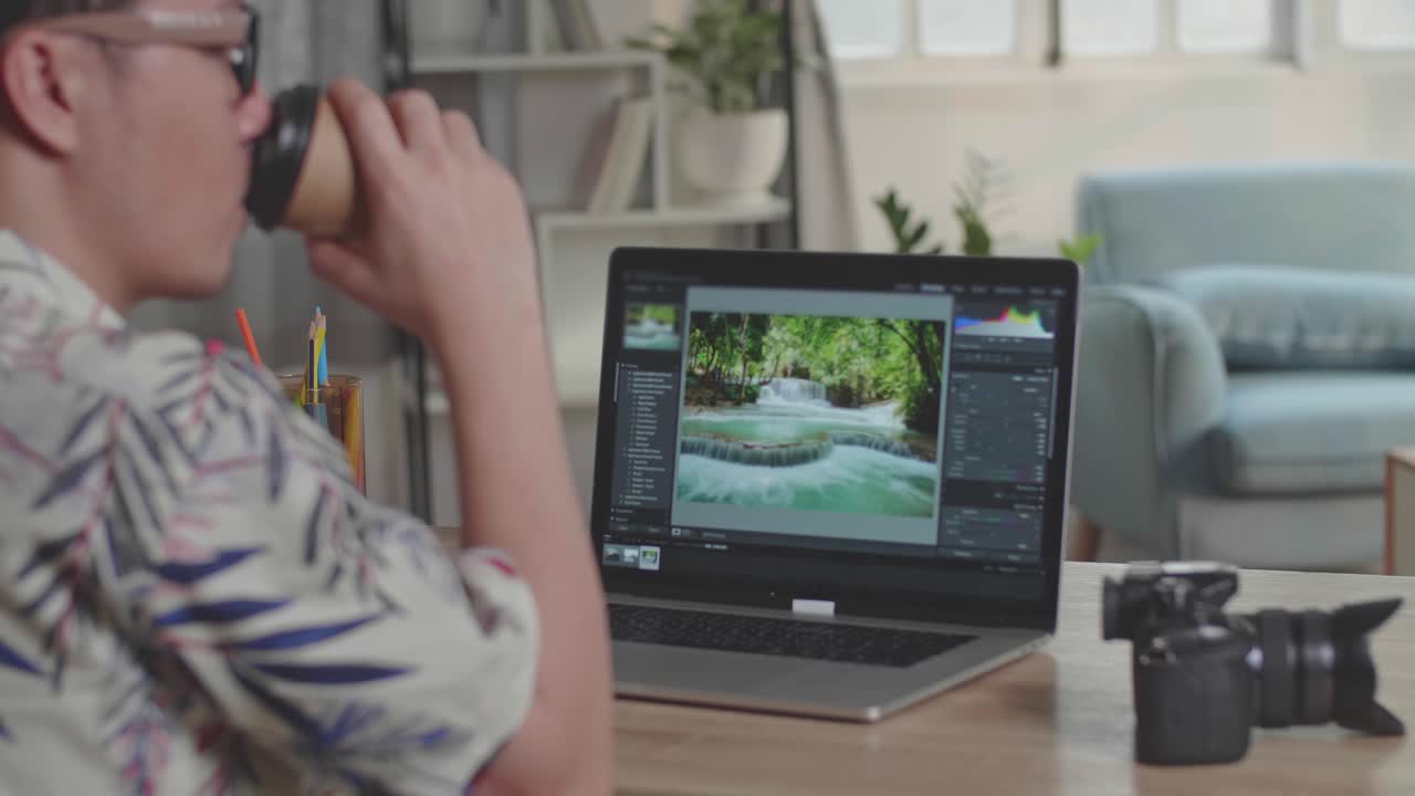 Photographer Drinking Coffee And Works In Photo Editing App / Software On His Laptop Computer