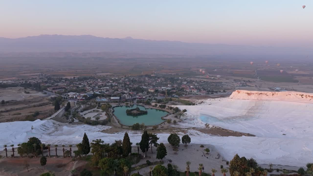 Sunrise skies and paragliders over Pamukkale travertine pools