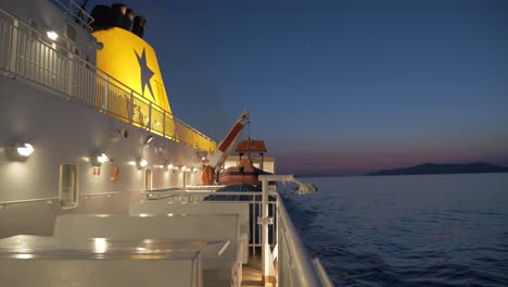 On-board-the-cruise-ship-that-takes-us-to-the-island-of-Amorgos,-we-can-see-the-sea-with-the-night-light-at-sunset,-wide-shot,-big-boat-with-chimney