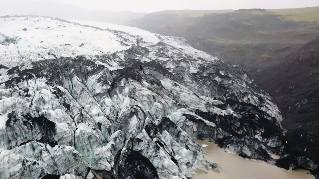 Aerial flight over a huge ice glacier in foggy mountains