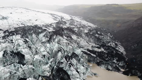 Aerial flight over a huge ice glacier in foggy mountains