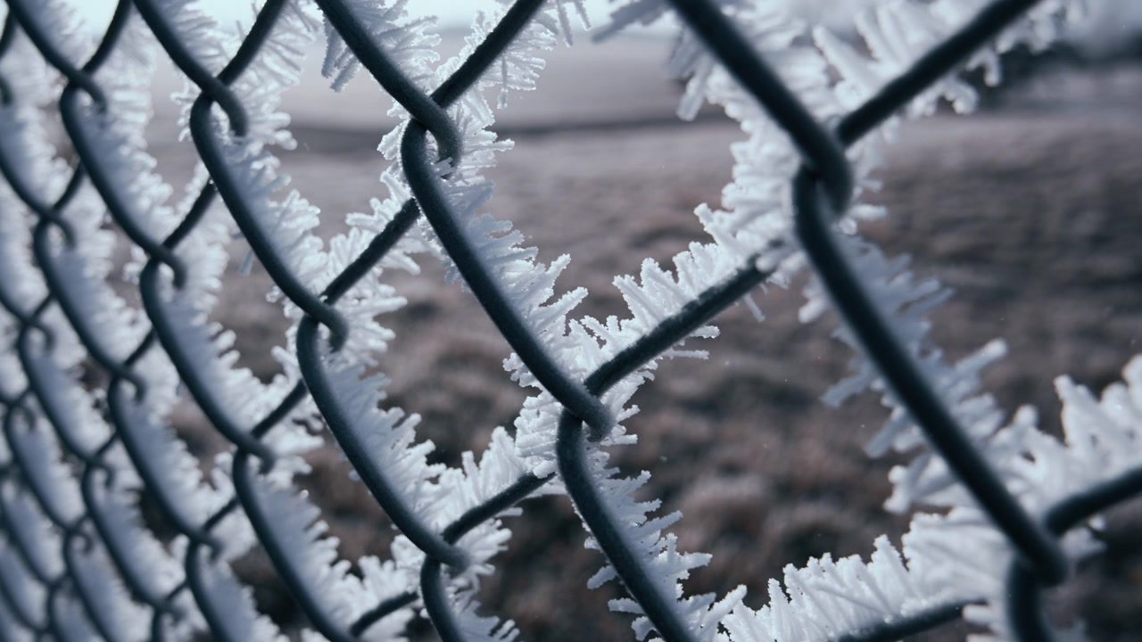 Metal fence covered in snow on a freezing morning in winter