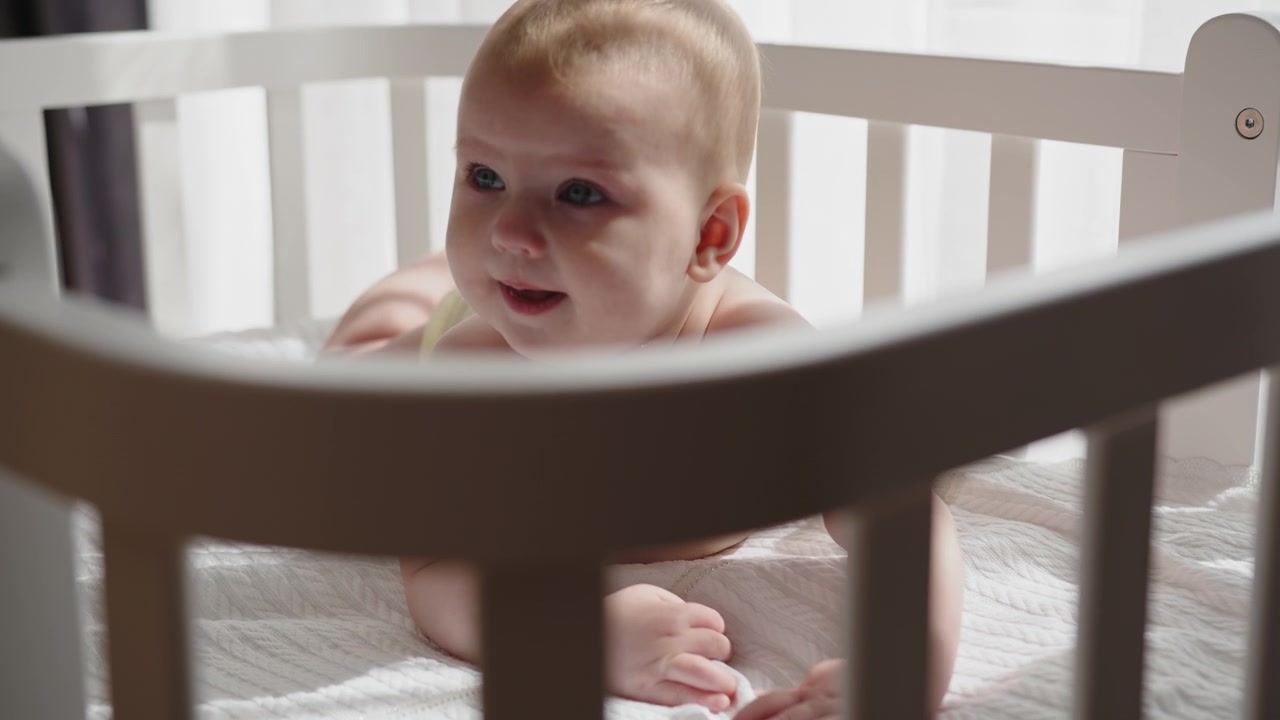 Baby playing in crib a baby joyfully plays in the crib where the infant child and newborn toddler