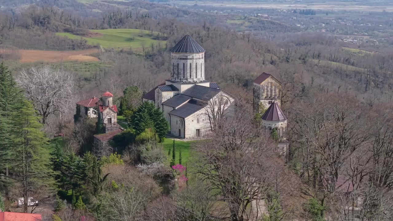 Drone orbit around Martvili Monastery, capturing the historic hilltop monastery surrounded by lush greenery and the scenic landscape of western Georgia.