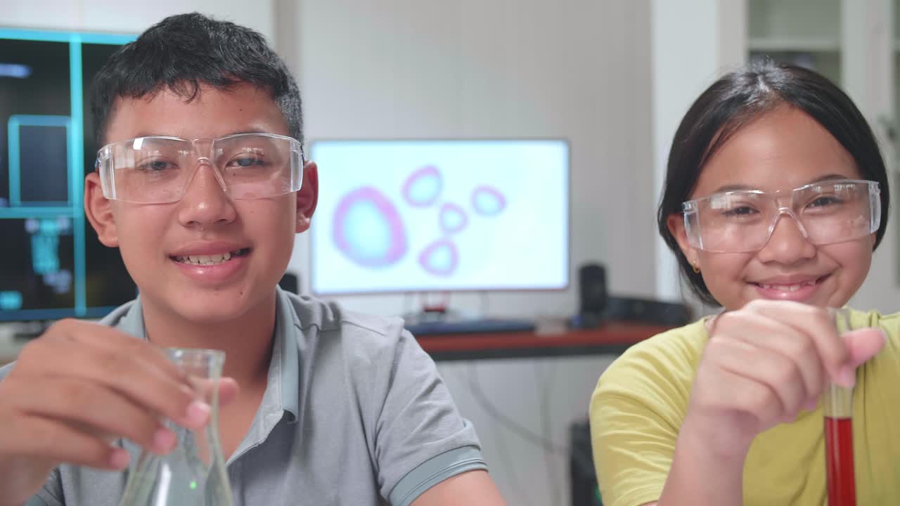 Young Asian Boy And Girl Smiling To Camera While Holding Tubes In Classroom. Study With Scientific Equipment. Education Concept