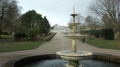 una pequeña fuente victoriana que fluye con agua al final de una larga pasarela hacia un hermoso pabellón