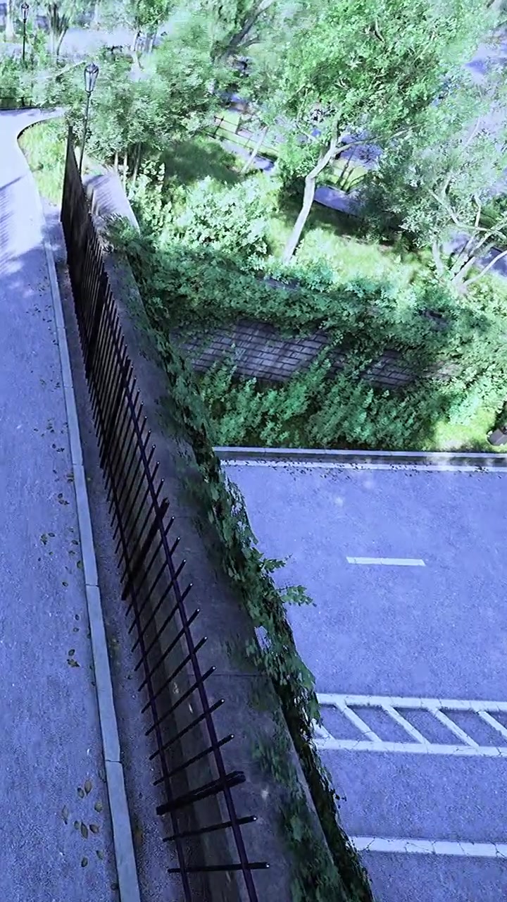 View of a road and green plants beside a fence on a sunny day
