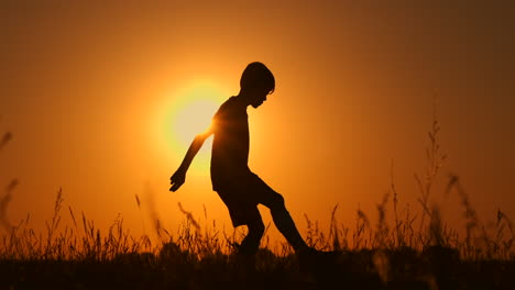 Silueta-De-Un-Niño-Jugando-Al-Fútbol-Al-Atardecer.-Un-Niño-Hace-Malabarismos-Con-Una-Pelota-En-El-Campo-Al-Atardecer.