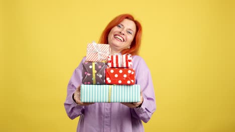 a happy red-haired woman holding a stack of colorful presents