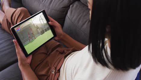 Composite-of-woman-on-couch-at-home-watching-hockey-match-on-tablet