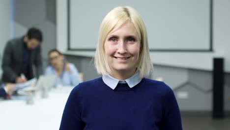 joyous mid-aged businesswoman posing in office