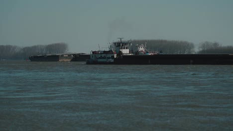 close up shot with two large barges navigating on a large river, clear sunny day