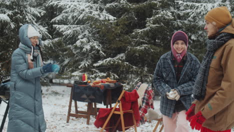 friends playing with snowball at campsite in winter forest