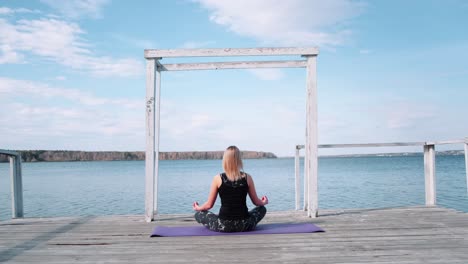 woman meditating on a pier by a lake