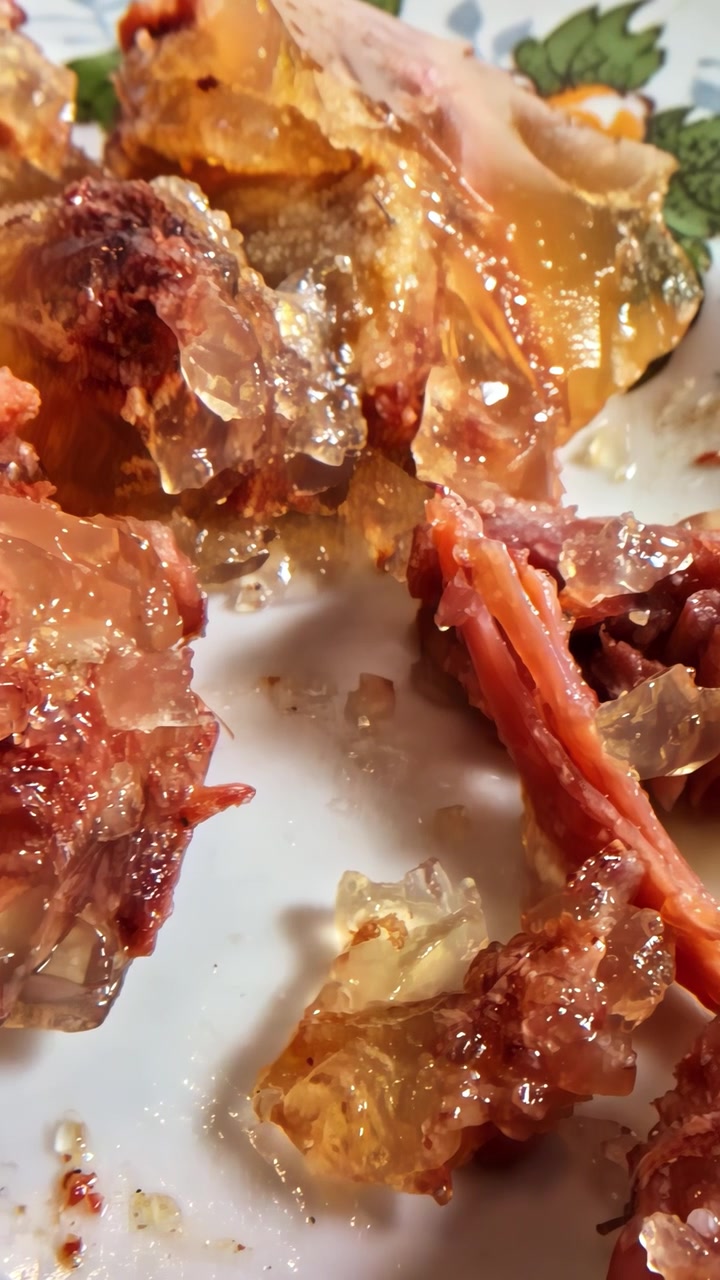 Aspic di carne tradizionale europeo con gelatina traslucida e carne sfilacciata su un piatto bianco, primo piano macro estremo, carrellata a sinistra.