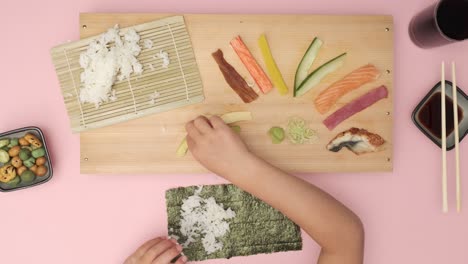 Top-shot-of-two-Hands-preparing-Sushi-on-rosy-table