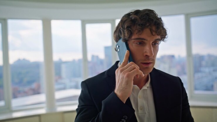 Uomo d'affari al telefono in un appartamento di lusso. Dirigente accanto a finestra panoramica