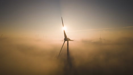silhouette of wind turbine casting shadows on clouds and fog below