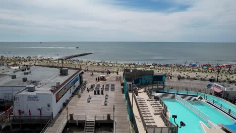 Aerial-drone-shot-showing-a-busy-boardwalk-and-a-crowded-beach-on-a-summer-day-at-the-Jersey-Shore