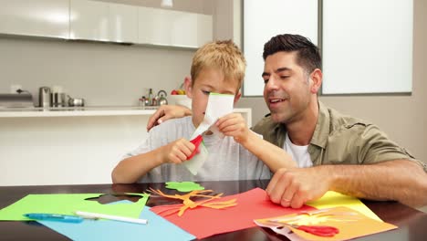 Happy-father-and-son-doing-arts-and-crafts-at-kitchen-table