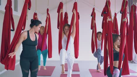 Entrenador-De-Fly-Yoga-Entrena-A-Mujeres-Delgadas-Practicando-Asanas-Guerreras