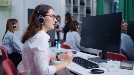 un grupo de mujeres trabajando en escritorios en un entorno de oficina, todas con auriculares y centrándose en sus pantallas de computadora