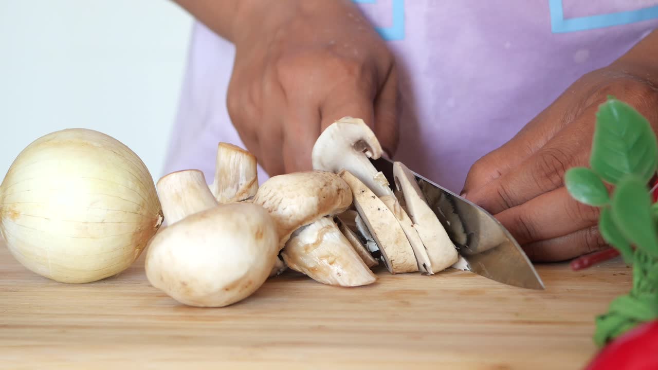 A woman chopping mushrooms and onions in the kitchen