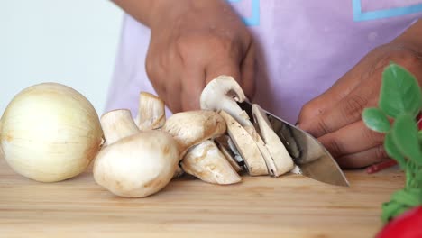 a woman chopping mushrooms and onions in the kitchen