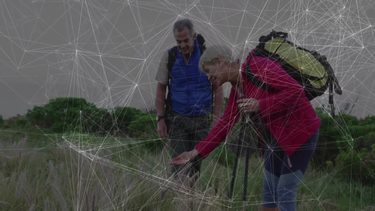 Mature hikers examining grasses in grassland, with animated health chart and backpack icon floating