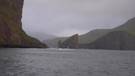 boat sailing through the north atlantic ocean heading towards drangarnir sea stacks arch