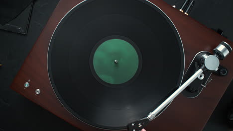 encendiendo un tocadiscos: colocando vinilo en el plato, girando y bajando el brazo de tono sobre el disco - vista de la mesa, cámara lenta, dolly out