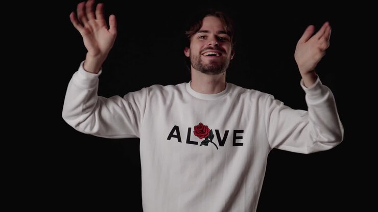 Trendy Young Man waving into camera with both hands, wide, black background