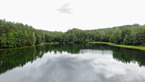 Impresionante-Paisaje-De-Lago-Sereno-Rodeado-De-Exuberantes-árboles-Coníferos-Verdes-En-Pradzonka,-Gmina-Studzienice,-Polonia