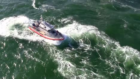 ariel view of a us coast guard vessel initially reversing, then moving forward along a travelled waterway