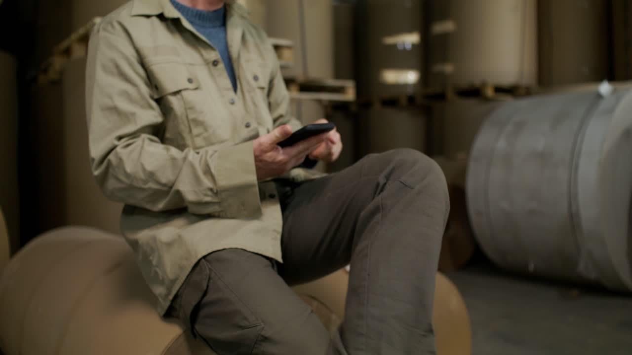 창고 직원이 스마트폰을 확인하고 있습니다.