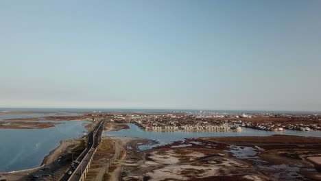 Aerial-drone-view-along-the-JFK-Memorial-Causeway,-storm-islands-and-waterfront-condominiums-on-North-Padre-Island-Texas-on-a-bright-sunny-afternoon