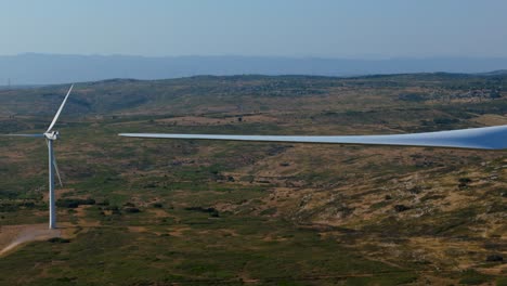 aerial tracking shot of a wind turbines blade in a large plant