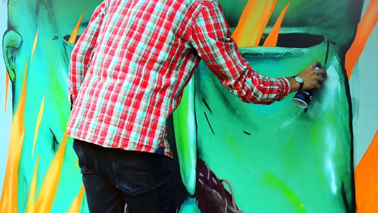 Konstnären målar graffiti på ett staket. Abstrakt teckning.