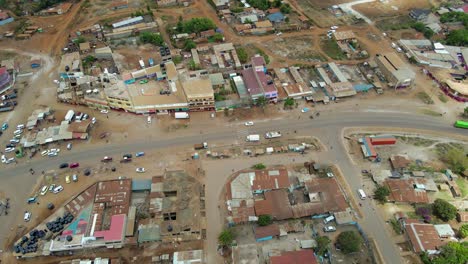 Aerial-view-of-a-town-and-sunlit-fields,-golden-hour-in-rural-Africa---tracking,-drone-shot