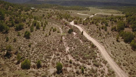 Aerial-of-dirt-road-with-Butte-Mesa-Flat-top-mountain-on-a-beautiful-day-in-desert-southwest-Colorado-USA