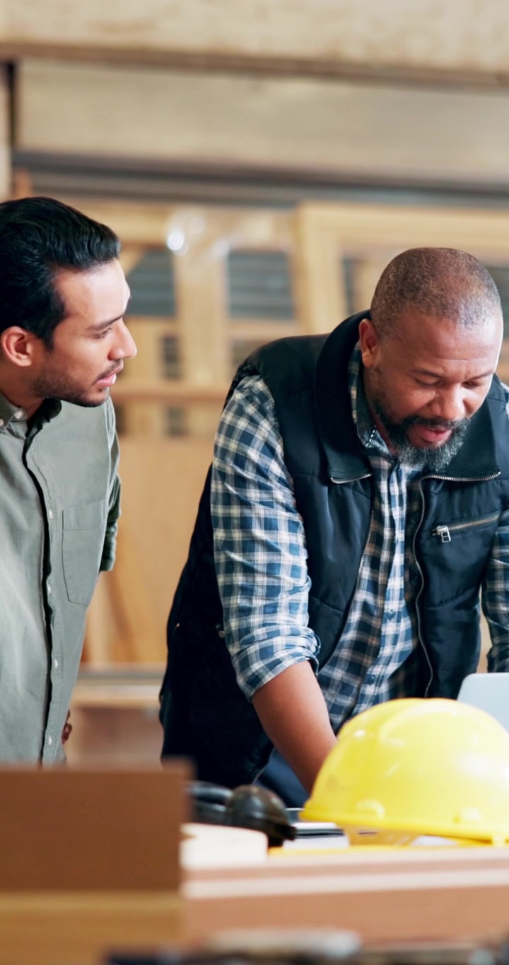 Two Construction Professionals Discussing Project Plans on Laptop in Workshop