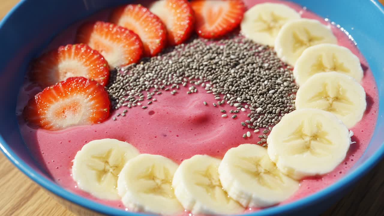 A Colorful Bowl of Smoothie Delight Featuring Fresh Strawberries, Bananas, and Chia Seeds on a Creamy Pink Base, Perfect for a Healthy Breakfast or Snack